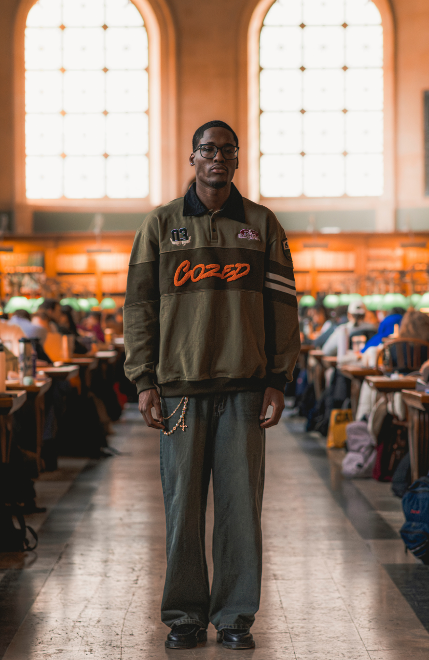 Man wearing a jacket with 'Cozed' branding in a large indoor setting with high ceilings and large windows.
